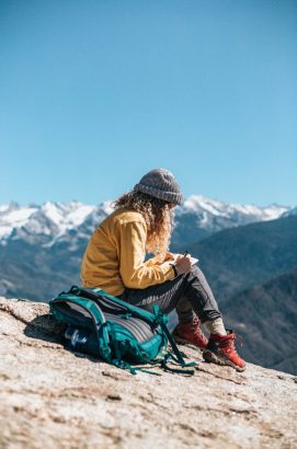 young-woman-writing-her-textbook-while-sitting-hill-near-mountain young-woman-writing-her-textbook-while-sitting-hill-near-mountain